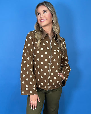 Brown polka dot zip-up jacket with a collared neckline, long sleeves, front pockets, and a relaxed fit.