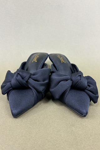 Pair of black shoes with large bows on a beige background
