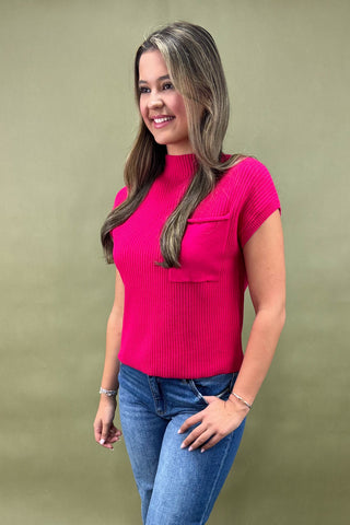 Woman wearing a pink sweater and blue jeans against a green background