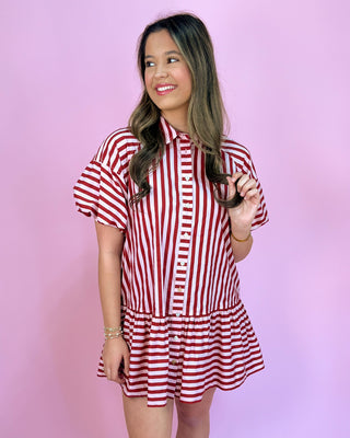 Woman wearing a red and white striped dress against a pink background