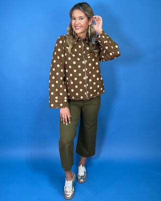Brown polka dot zip-up jacket with a collared neckline, long sleeves, front pockets, and a relaxed fit.