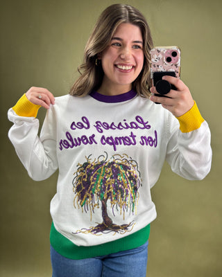 Woman wearing a white sweatshirt with a colorful design and text, taking a selfie.