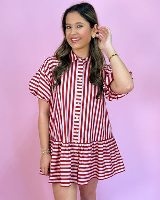 Woman wearing a red and white striped dress against a pink background