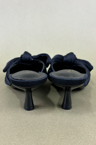 Pair of black shoes with bow details on a beige background