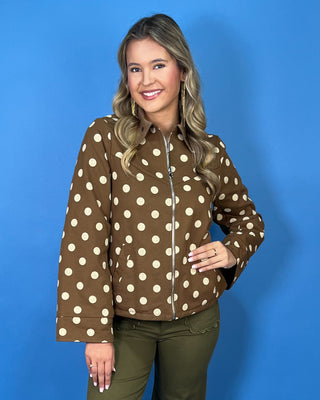 Brown polka dot zip-up jacket with a collared neckline, long sleeves, front pockets, and a relaxed fit.