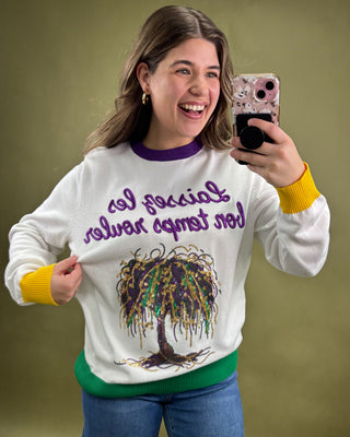 Person wearing a sweater with a colorful design and text, taking a selfie against a green background