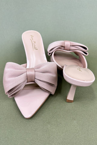 Pink high-heeled shoes with large bows on a light green background
