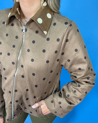 Brown polka dot zip-up jacket with a collared neckline, long sleeves, front pockets, and a relaxed fit.