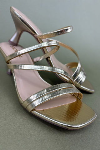 Silver high-heeled sandals on a gray background