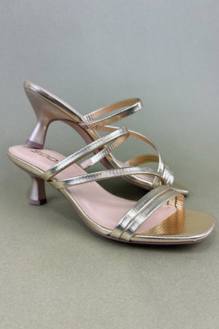 Gold high-heeled shoe on a gray background