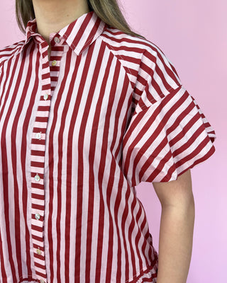 Red and white striped shirt worn by a person on a pink background