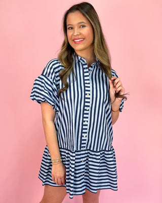 Woman wearing a blue and white striped dress against a pink background