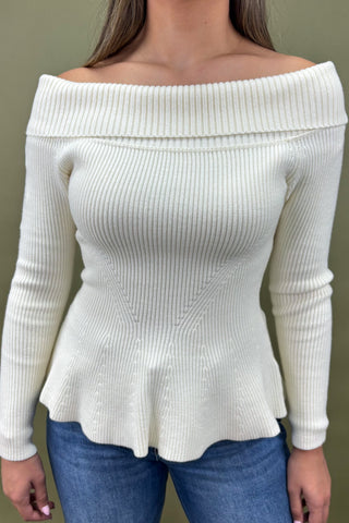 White off-shoulder sweater worn by a person against a plain background