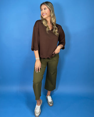 Chocolate brown collared top with a V-neckline, three-quarter sleeves, and scalloped trim along the cuffs and hem.