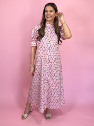 Woman wearing a pink floral dress against a pink background
