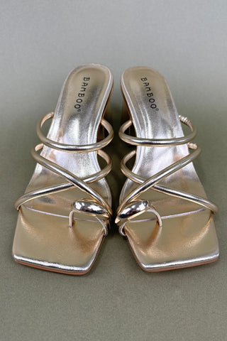Pair of silver high-heeled sandals on a gray background