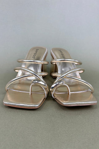 Silver high-heeled sandals on a light gray background