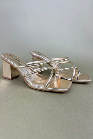 Silver high-heeled sandals on a light gray background