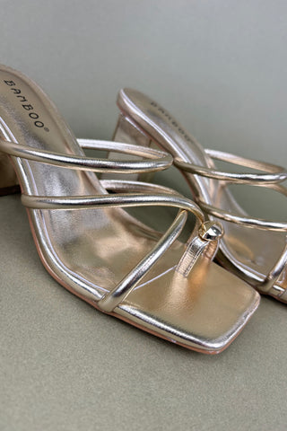 Silver high-heeled shoes with 'Birkenstock' branding on a light gray background
