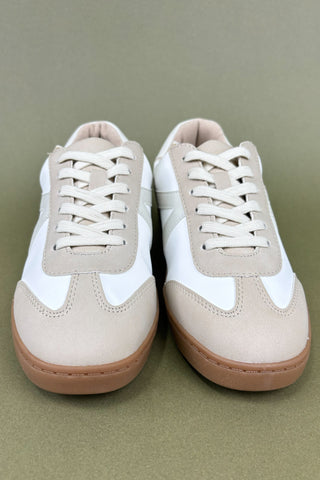 Pair of beige and white sneakers on a green background