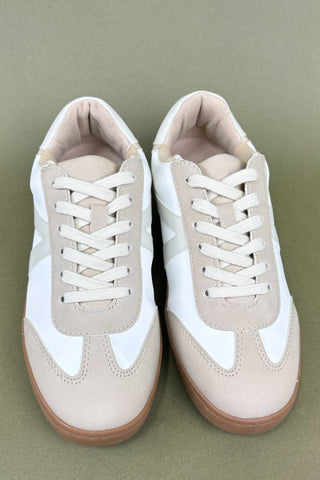 Pair of beige and white sneakers on a green background