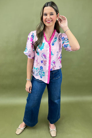 Woman wearing a colorful floral blouse and blue jeans on a green background