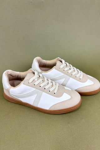 Pair of beige and white sneakers on a green background