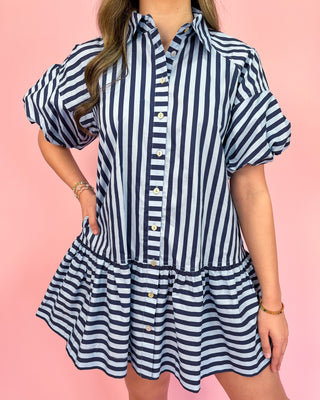 Navy and white striped dress worn by a person on a pink background