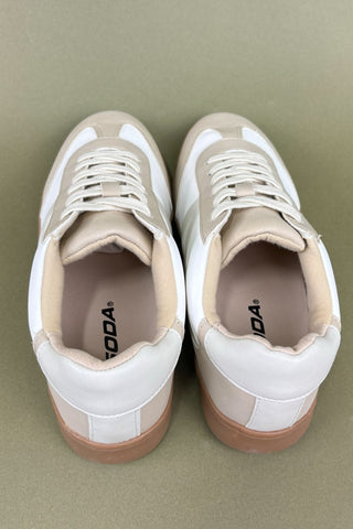 Pair of beige and white sneakers on a light green background