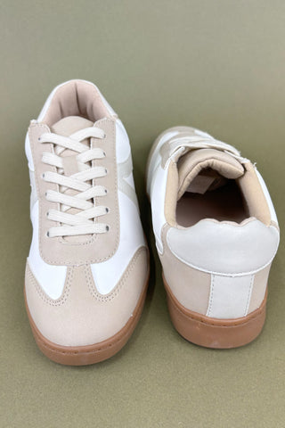 Pair of beige and white sneakers on a green background