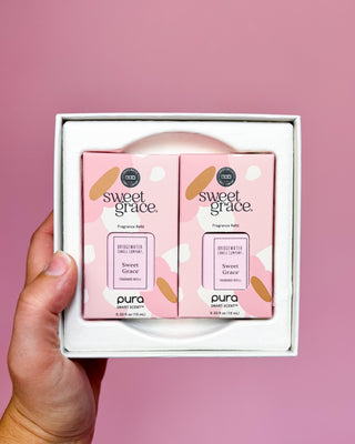 Two 'sweet grace' candles in a box held against a pink background