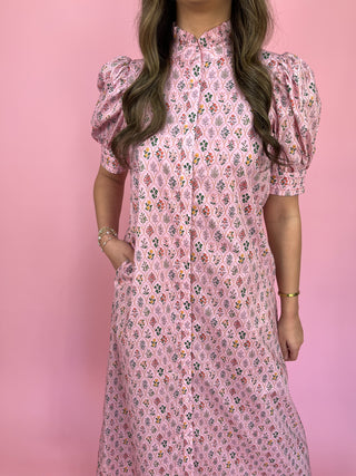 Woman wearing a pink floral dress against a pink background