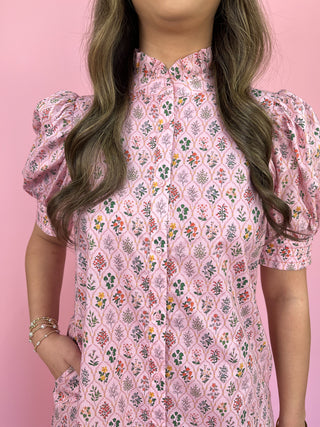 Person wearing a pink floral dress against a pink background