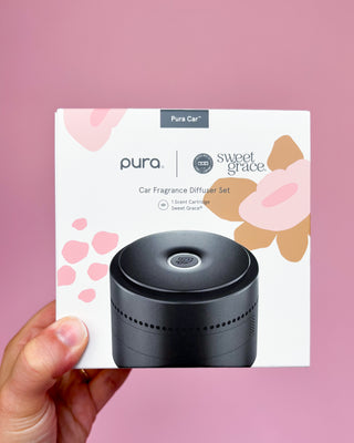 Pura Car fragrance diffuser set packaging with a pink floral design on a pink background