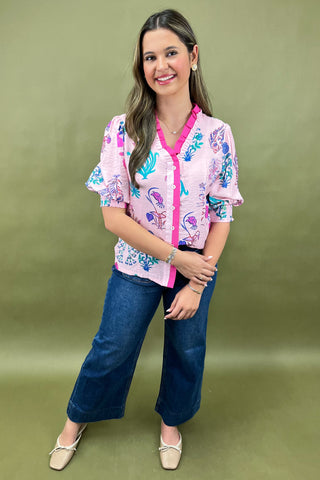 Woman wearing a colorful floral blouse and blue jeans on a green background