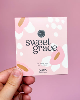 Pura Sweet Grace car diffuser refill packaging held against a pink background