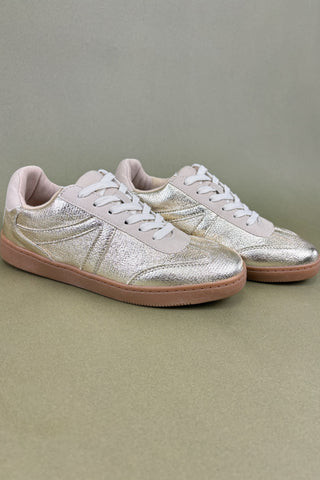 Pair of glittery sneakers on a beige background