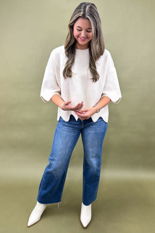 Woman wearing a white blouse and blue jeans against a green background