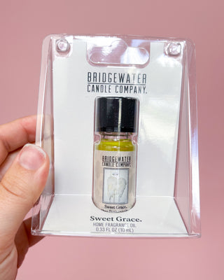 Bridgewater Candle Company Sweet Grace home fragrance oil in packaging held by a hand against a pink background