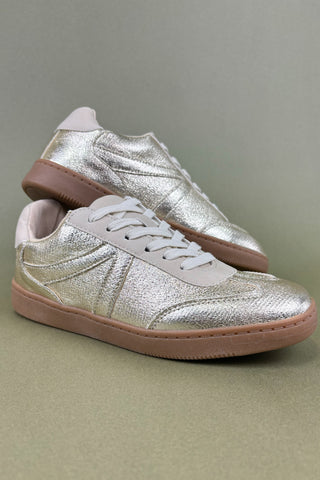Pair of silver sneakers with brown soles on a gray background