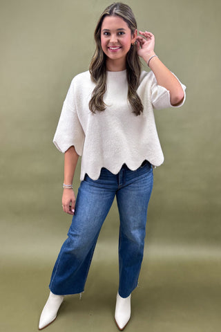 Woman wearing a white blouse and blue jeans against a green background