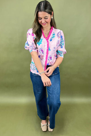 Woman wearing a colorful floral blouse and blue jeans on a green background