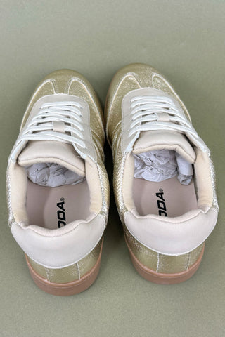 Pair of beige sneakers with white laces on a light gray background
