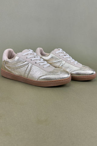 Pair of silver glitter sneakers with brown soles on a gray background