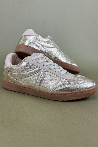Silver sneakers with brown soles on a gray background