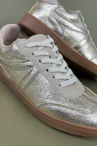 Silver sneakers with brown soles on a green background