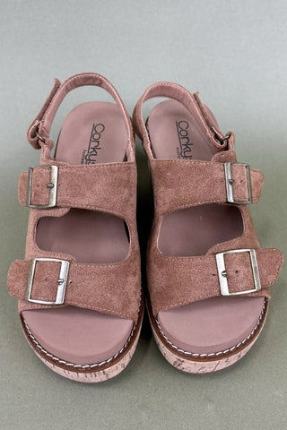 Pair of pink suede sandals with buckles on a gray background