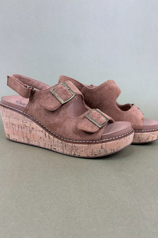 Pair of brown wedge sandals with cork sole on a gray background
