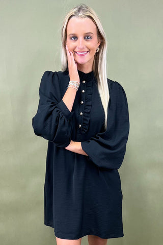 Woman wearing a black dress against a green background