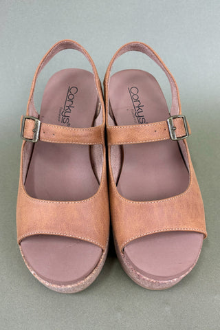 Pair of tan sandals with pink soles on a gray background